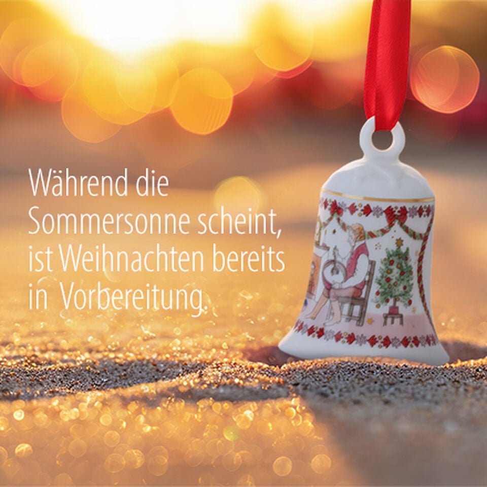 Porzellan-Weihnachtsglocke h&auml;ngt auf einem Zweig mit roten Beeren in Weihnachtsstimmung