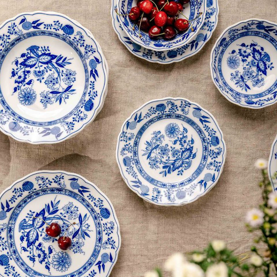 Onion pattern plates on linen cloth, some decorated with cherries