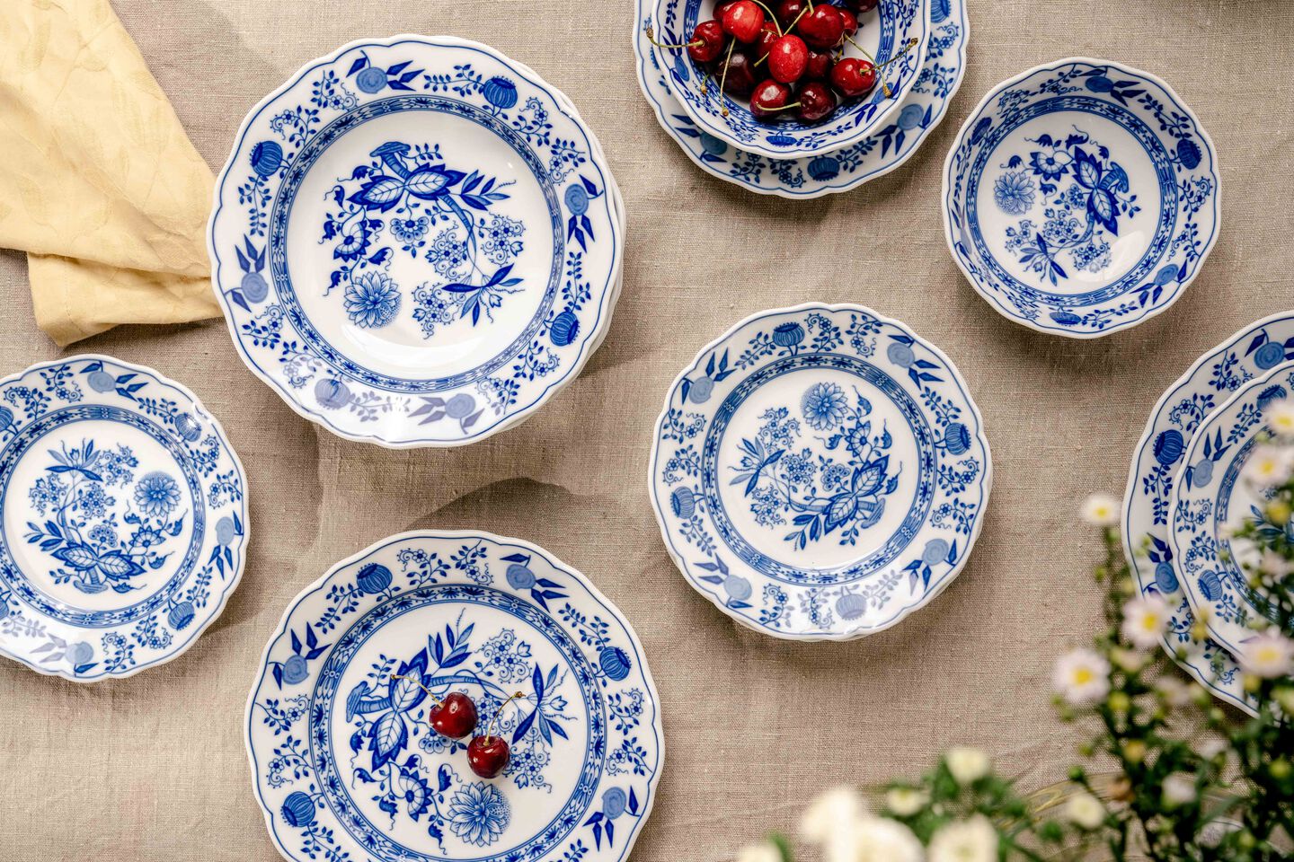 Hutschenreuther blue onion pattern plates on linen cloth, bowl with cherries.