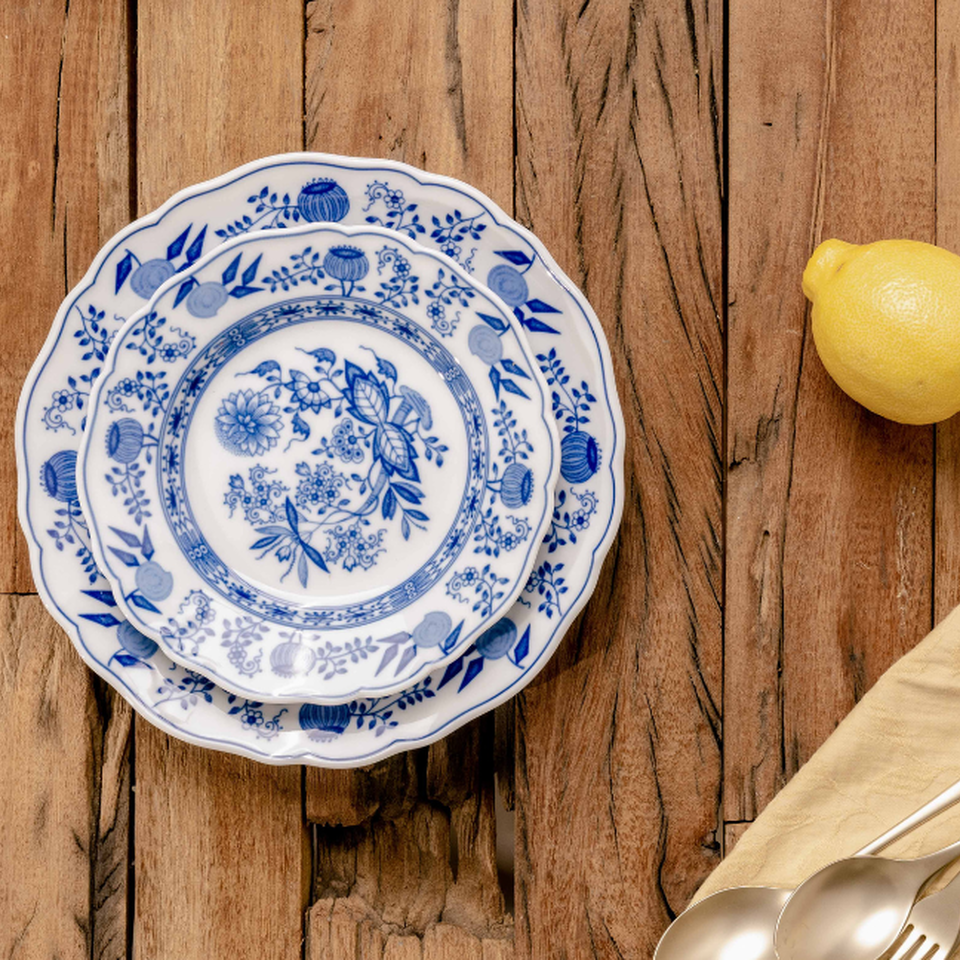 Classica porcellana Hutschenreuther blu e bianca con decorazione a cipolla, disposta su un sottofondo di legno con limone e tovagliolo di stoffa.
