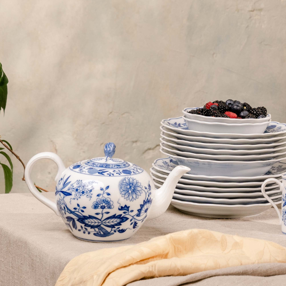Teapot and stacked blue onion plates with berries.