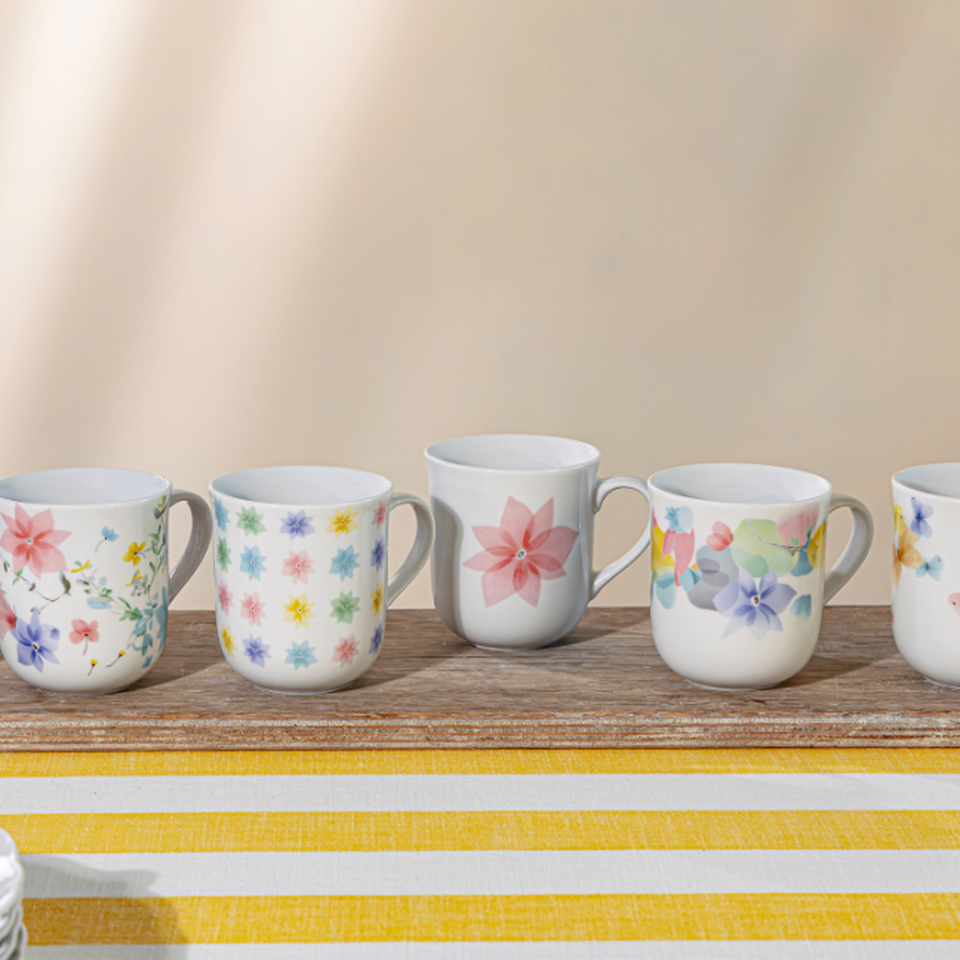 Tazza primaverile Hutschenreuther con delicati motivi floreali come decorazione pasquale su una tovaglia a righe gialle e bianche