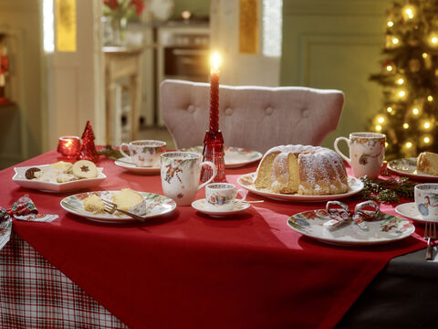Festlich gedeckter Tisch mit Porzellan, Kuchen und Kerze.