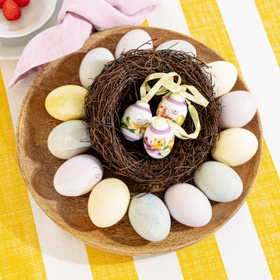 Decorazioni pasquali Hutschenreuther con uova di Pasqua in porcellana nel nido su una tavola pasquale a strisce gialle e bianche