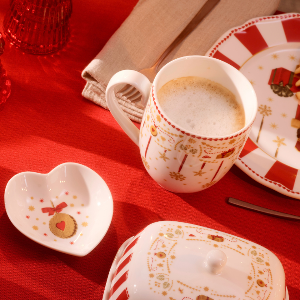 Tazza natalizia con caff&egrave; latte su una tovaglia rossa.
