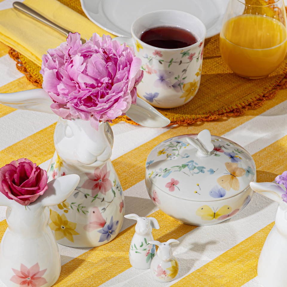 Decorazioni pasquali Hutschenreuther con porcellana floreale, decorazioni floreali e peonie rosa su una tavola pasquale a strisce gialle e bianche