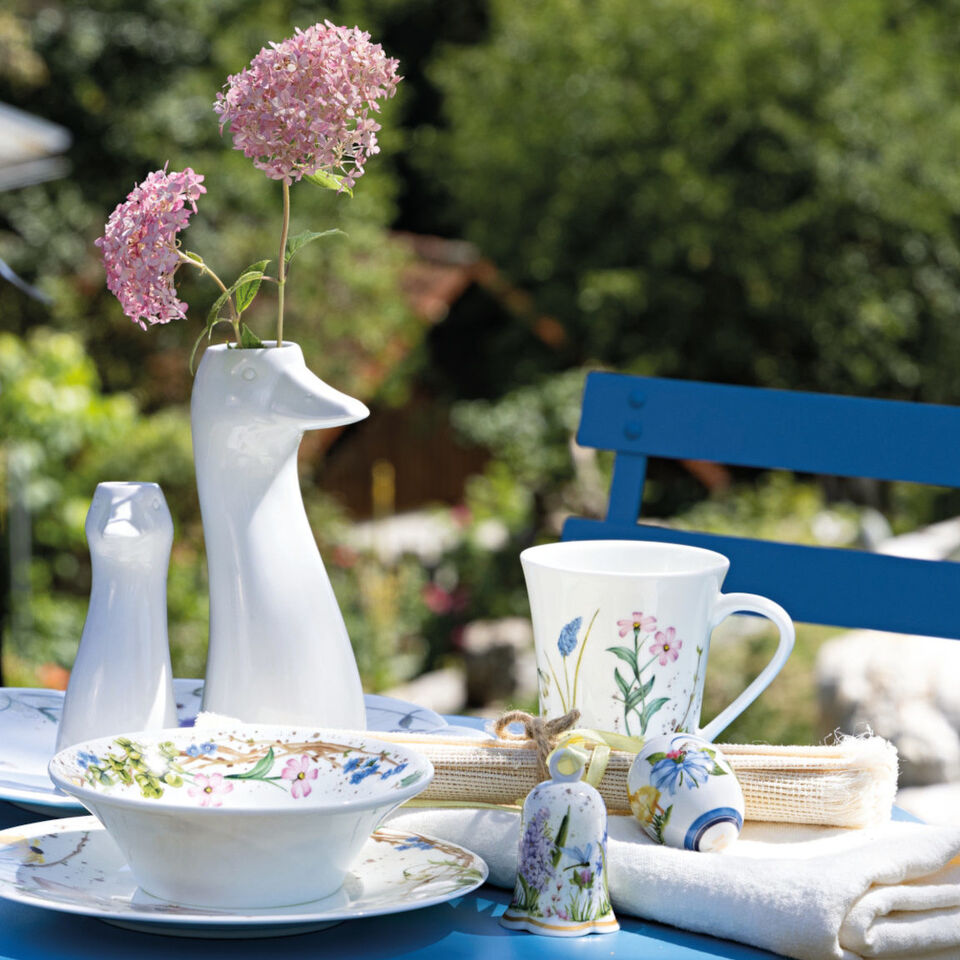 Porcellana primaverile Hutschenreuther con decorazioni floreali come elegante decorazione pasquale sul tavolo da giardino apparecchiato