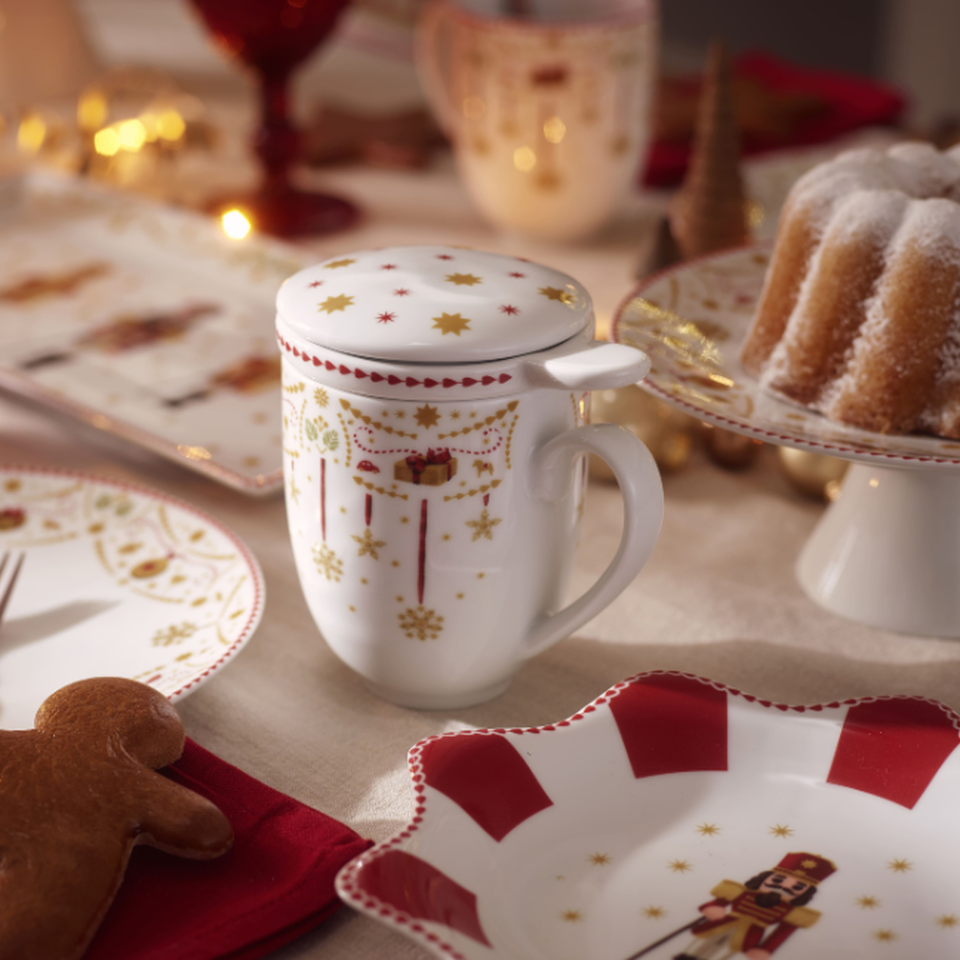 Tazza da t&egrave; natalizia con decorazioni rosse su una tavola imbandita a festa.
