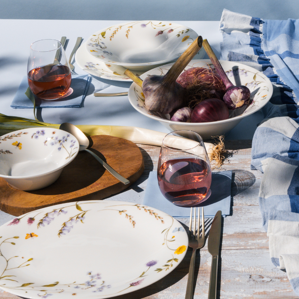 Tavola primaverile con piatti floreali Rosenthal, vino rosé e ingredienti freschi – apparecchiata con eleganza all’aperto.