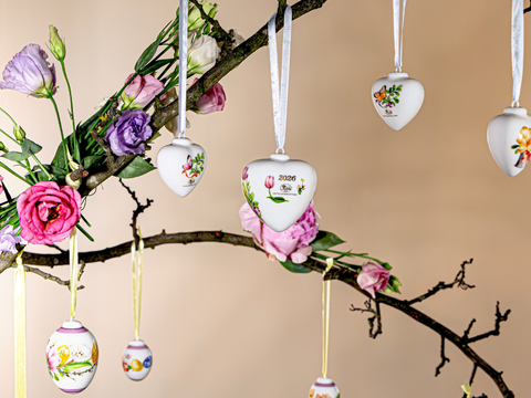 Several easter pendants hanging on a branch with flowers on the left side