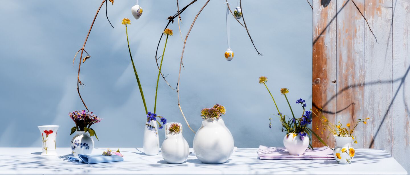 Arrangement of Rosenthal vases with delicate spring flowers against a light blue background – Artistic porcelain design.