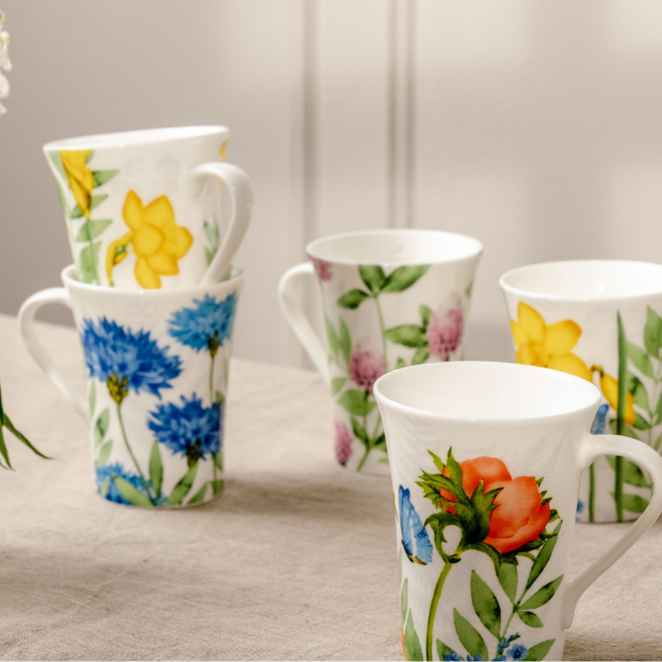 Tazze in porcellana floreali Rosenthal con motivi floreali dettagliati – disposte con eleganza su un tessuto di lino.