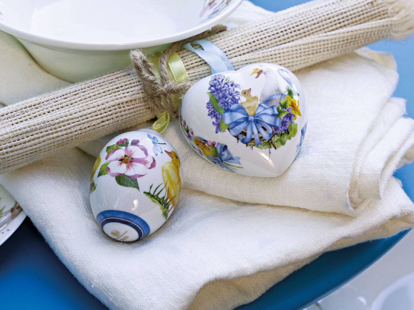 Hutschenreuther Osteranhänger Herz und Ei auf weißer Serviette auf blauem Tisch