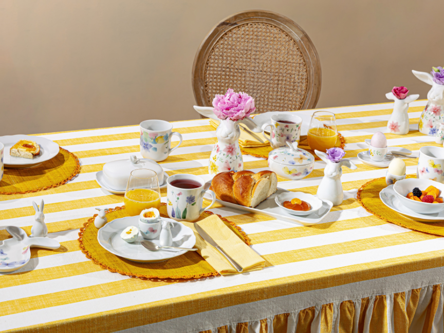 Hutschenreuther Easter tableware with floral decoration on a yellow and white striped table, decorated with cups, plates, flowers and spring-like accents.