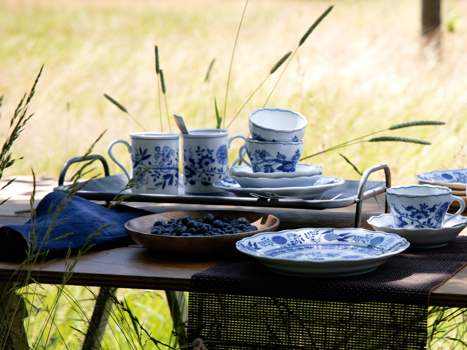 Hutschenreuther Blau Zwiebelmuster Geschirr auf einem Holztisch mitten in einer Sommerwiese