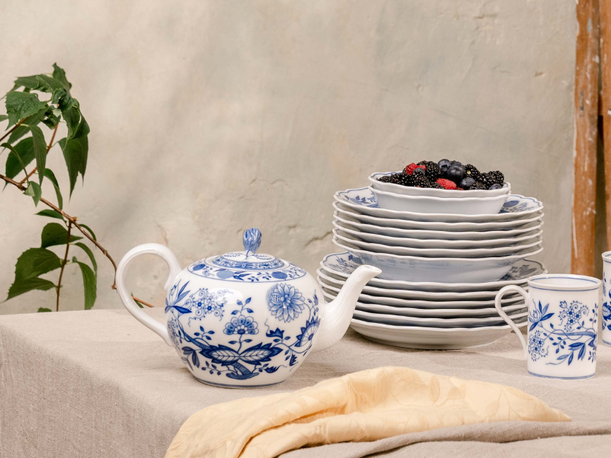 Teiera e piatti impilati con decoro cipolla e frutti di bosco.