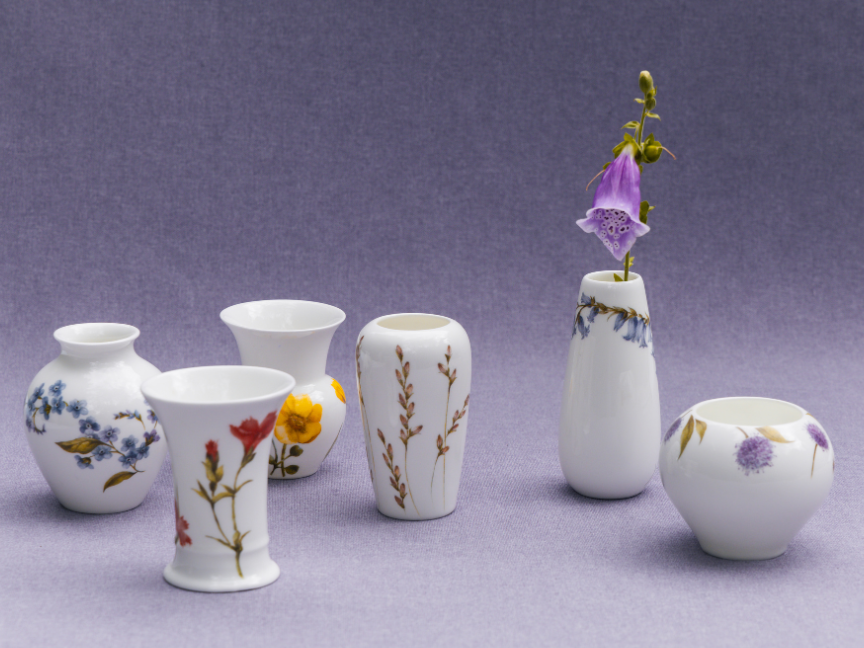 Small Rosenthal porcelain vases with delicate floral motifs on a violet fabric background – subtle elegance in series.