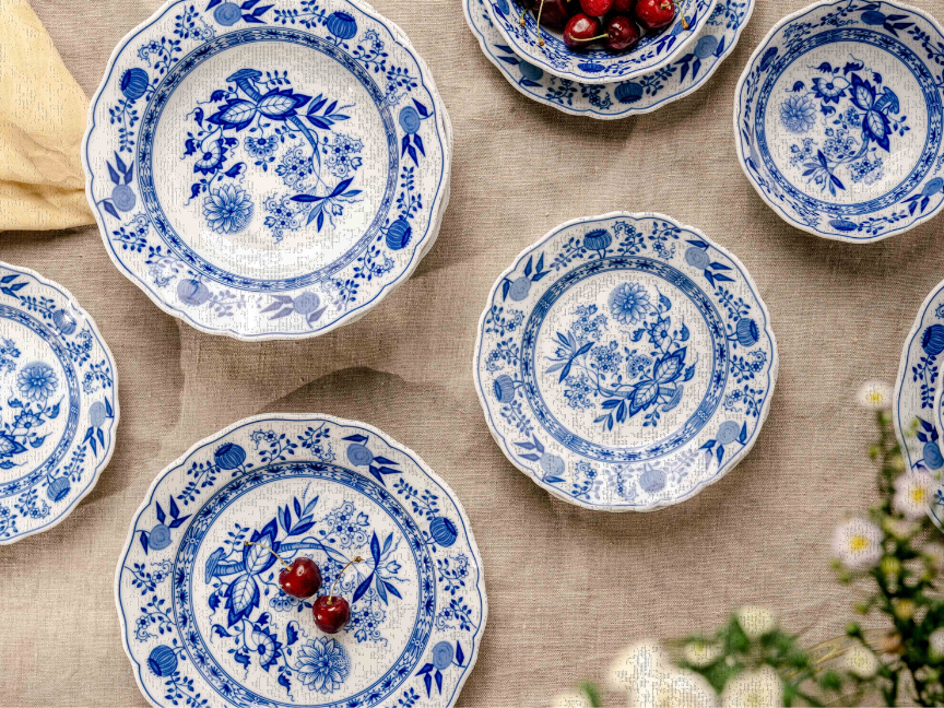 Hutschenreuther tableware with blue onion pattern decoration arranged on light linen cloth, decorated with small red berries.