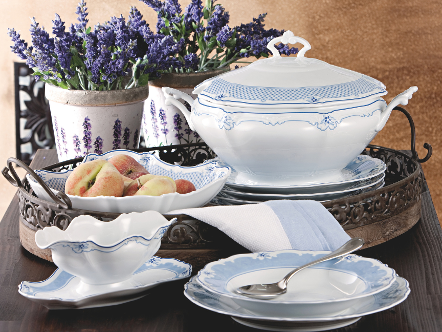 Elegant Hutschenreuther Baronesse porcelain tableware in white and blue with floral decoration, arranged on a tray with a tureen, bowls and lavender in the background.