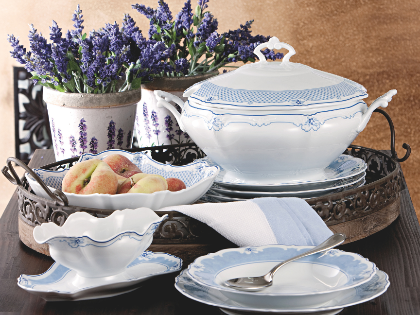 Elegant blue and white Hutschenreuther dinner service with soup tureen, bowls and plates in front of pots with lavender blossoms