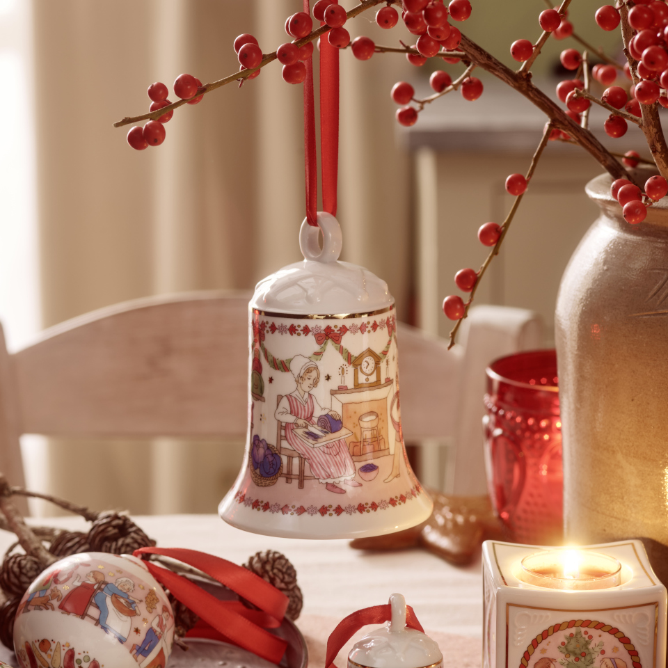 Porcelain Christmas bell hanging on a branch with red berries