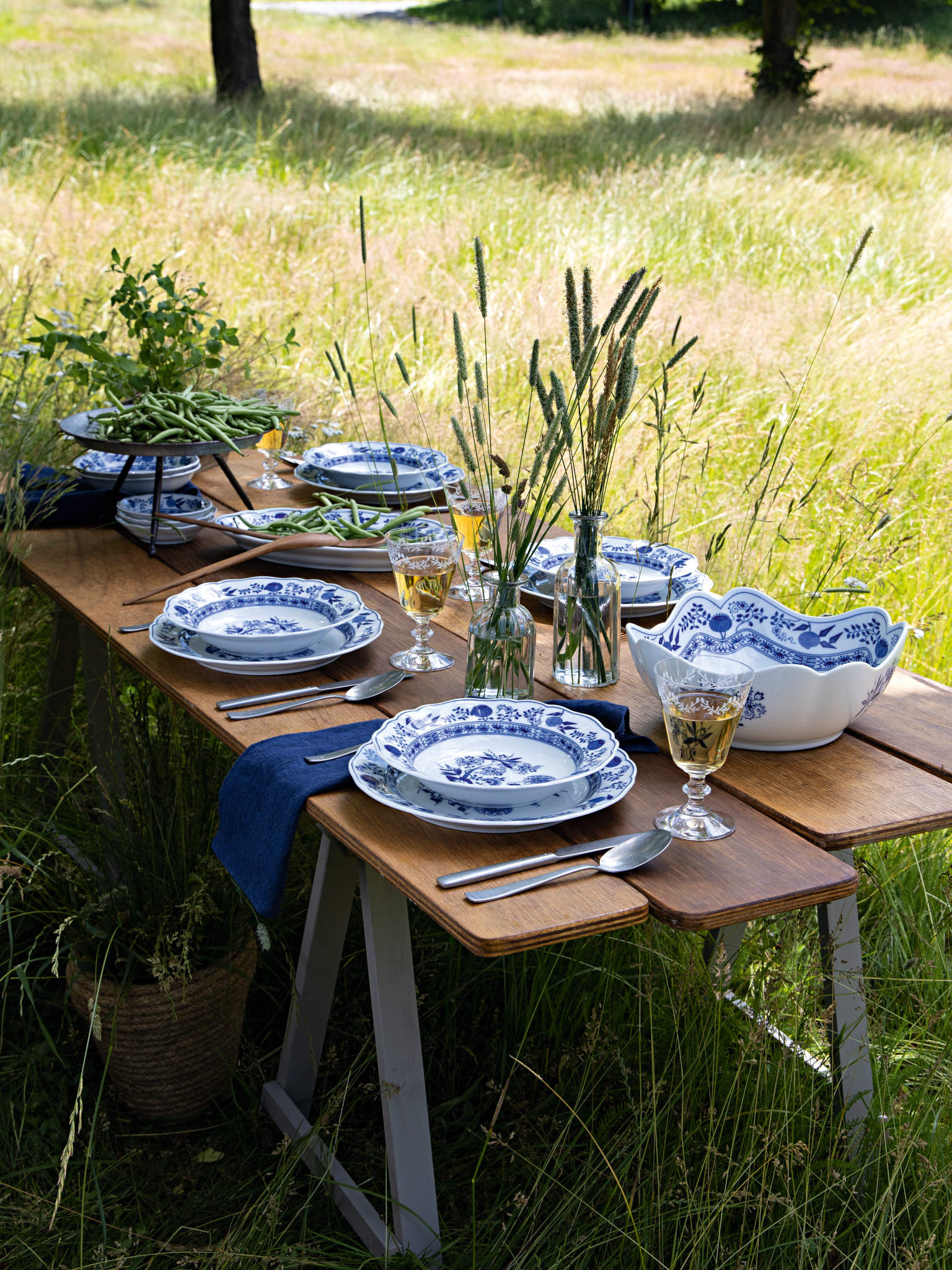 Hutschenreuther Blau Zwiebelmuster Geschirr auf einem Holztisch mit Sommerwiese im Hintergrund