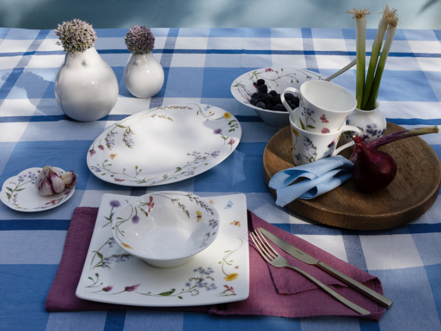 Hutschenreuther tableware with a delicate floral pattern on a blue and white checked tablecloth, arranged with plates, bowls, cups and spring decorations.