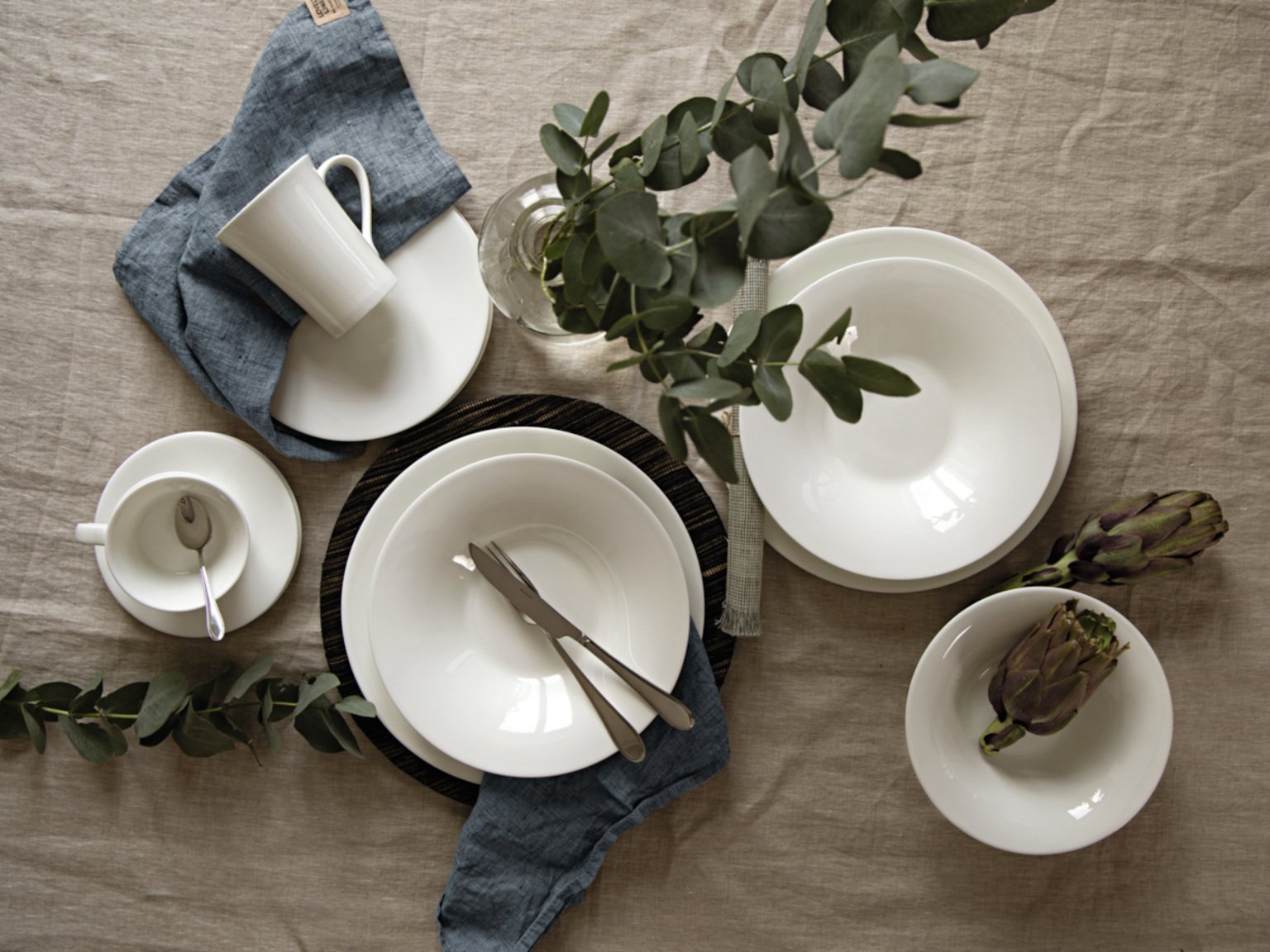 Hutschenreuther Nora White dining collection arranged on linen tablecloth and eucalyptus branches